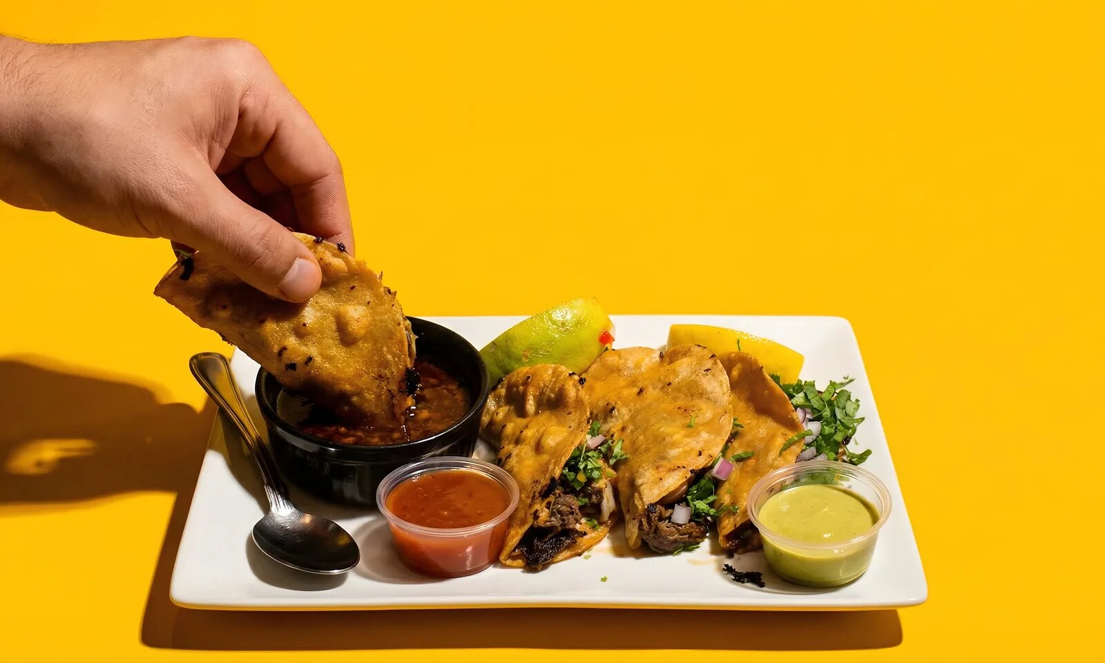 Birria tacos with consomé, salsas, and limes